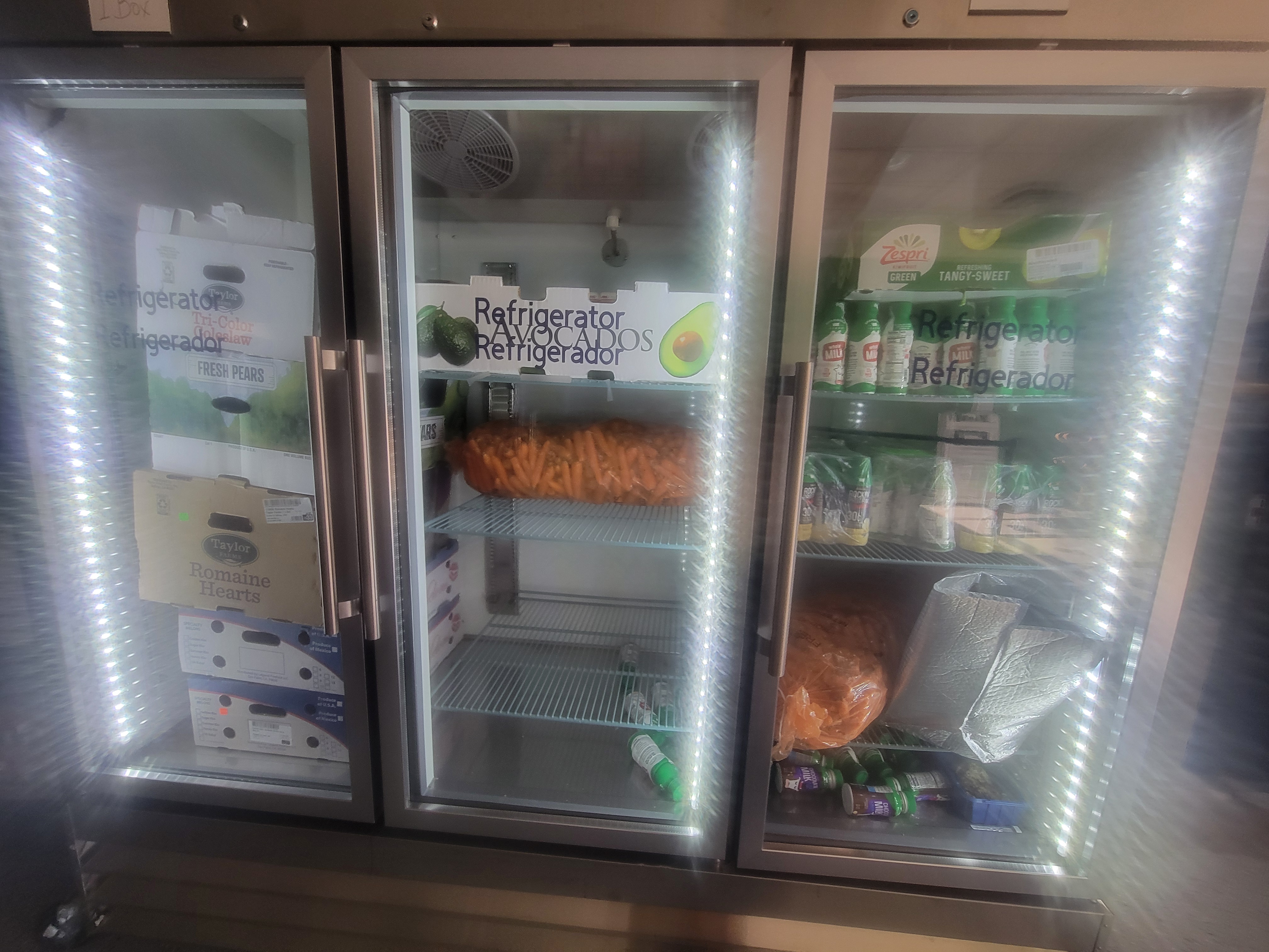 Fridge unit full of produce, milks, and boxes.